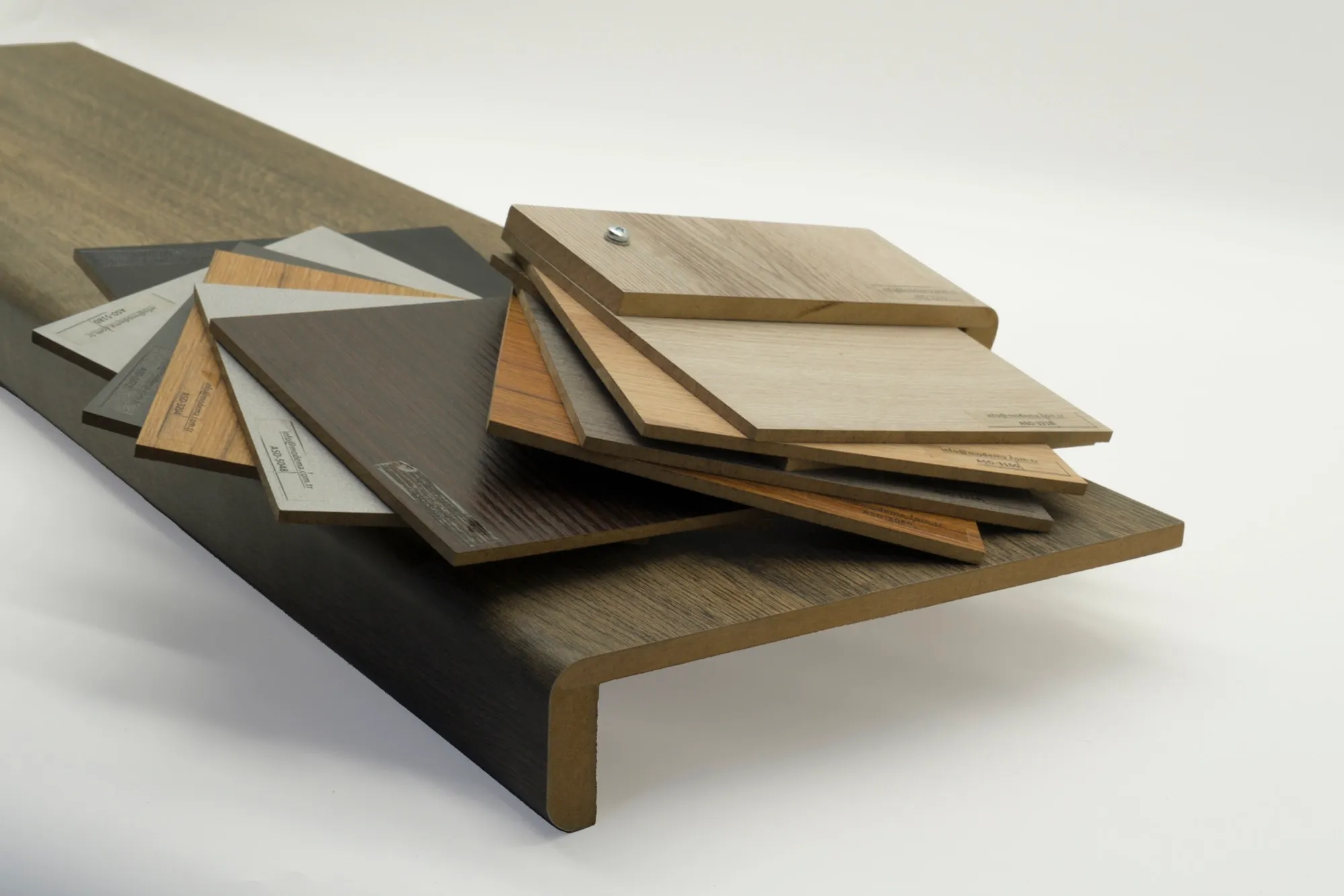 Fanned wood-finish sample chips displayed on a Modema stair nosing profile